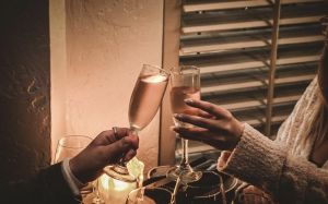 couple seated at restaurant cheering with champagne glasses